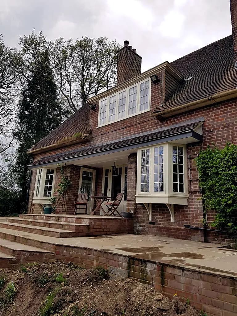 Red-brick house with timber bay casement windows and a covered porch