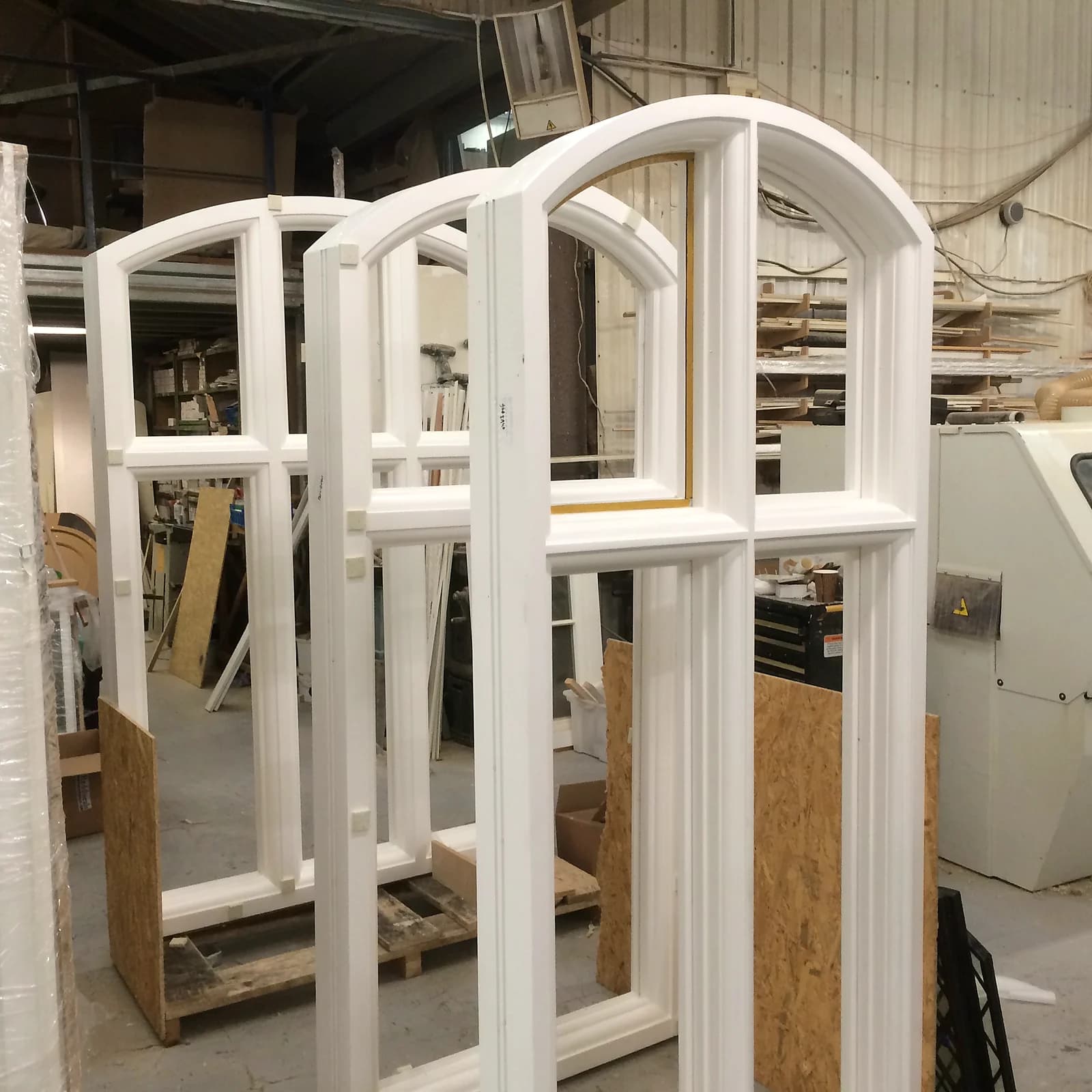 Three arched-head timber casement windows under construction in the workshop