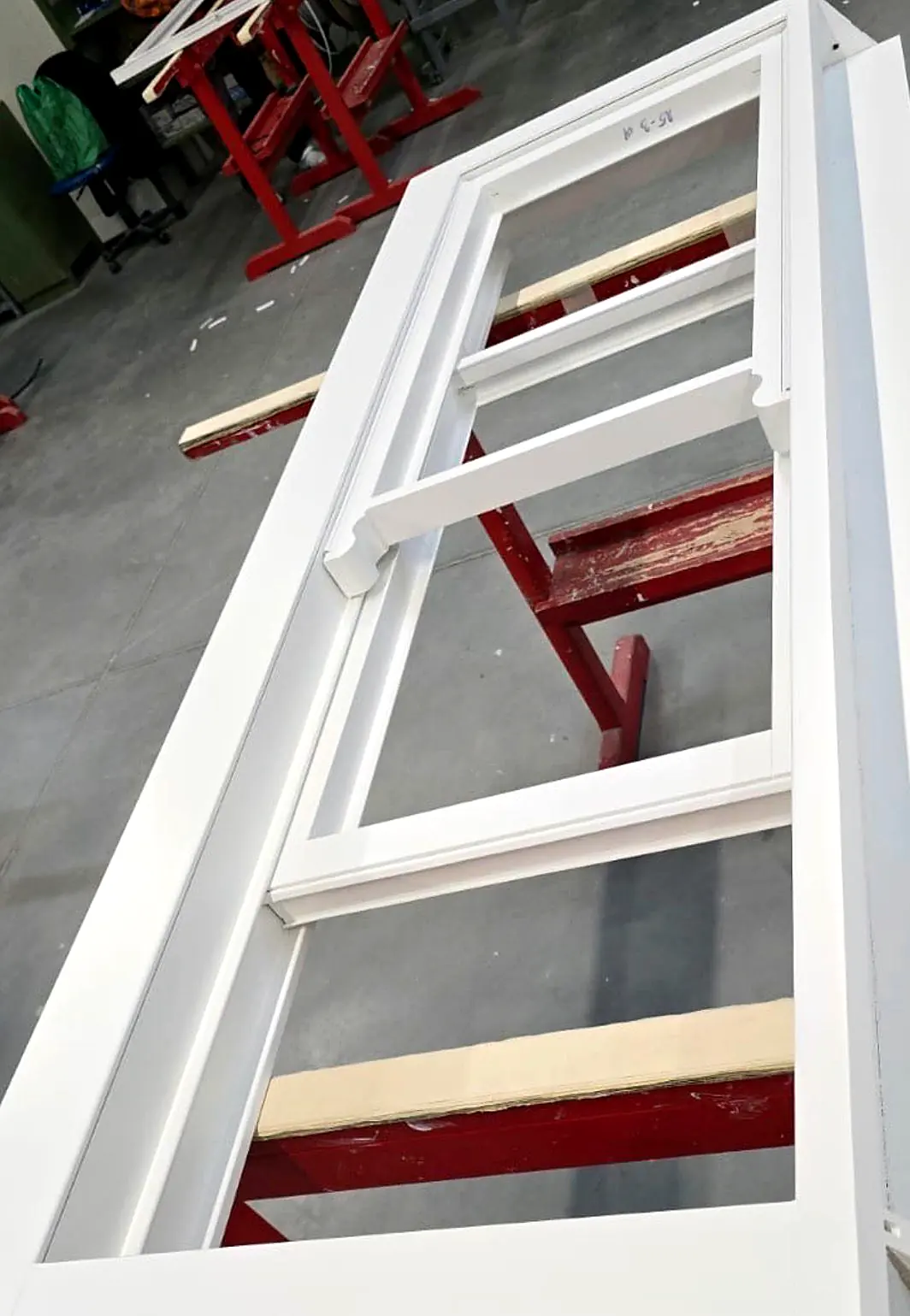 Freshly sprayed white timber window sections drying on workshop racking