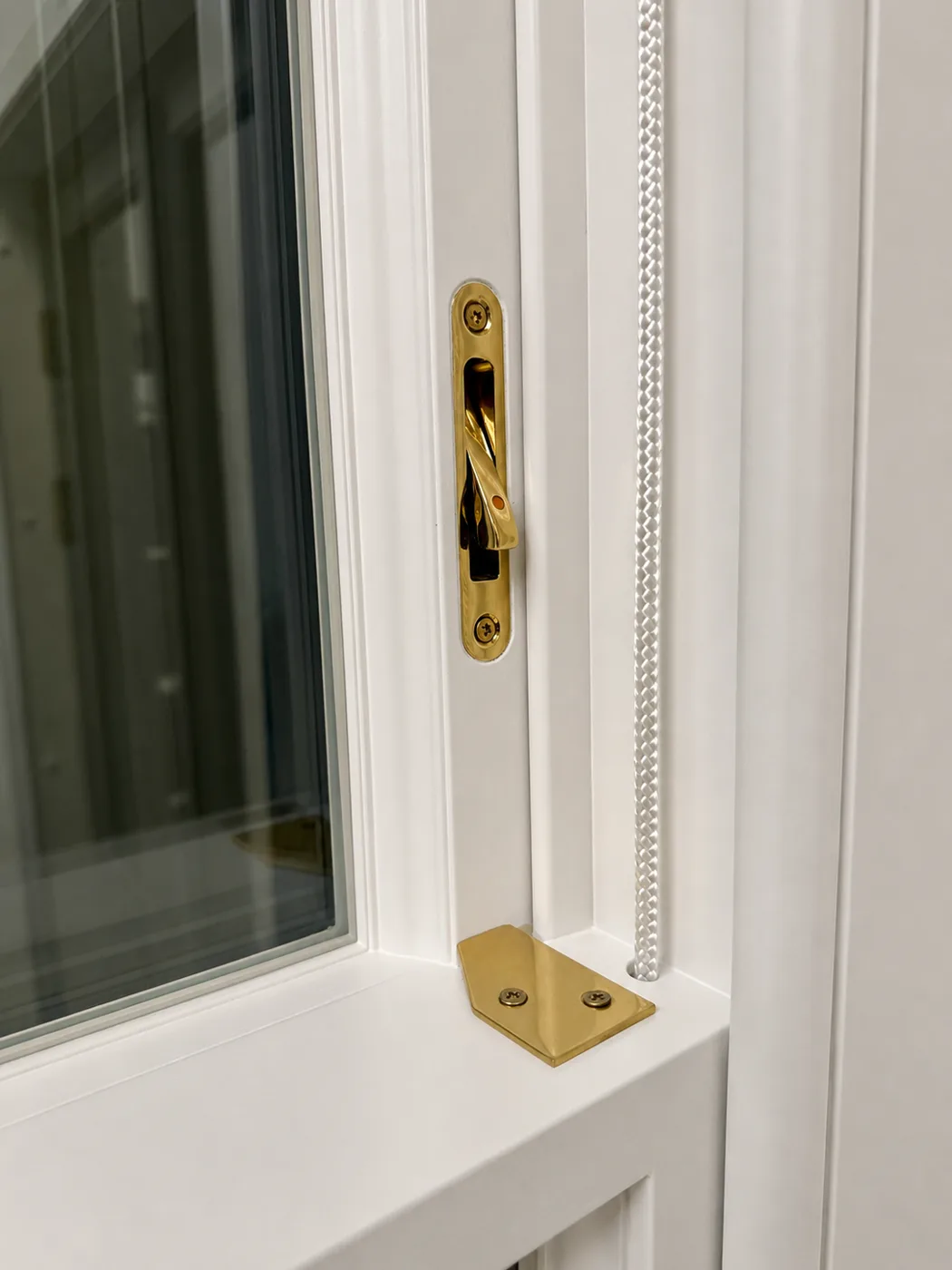 Brass Angel restrictor pre-fitted to a white timber sash window