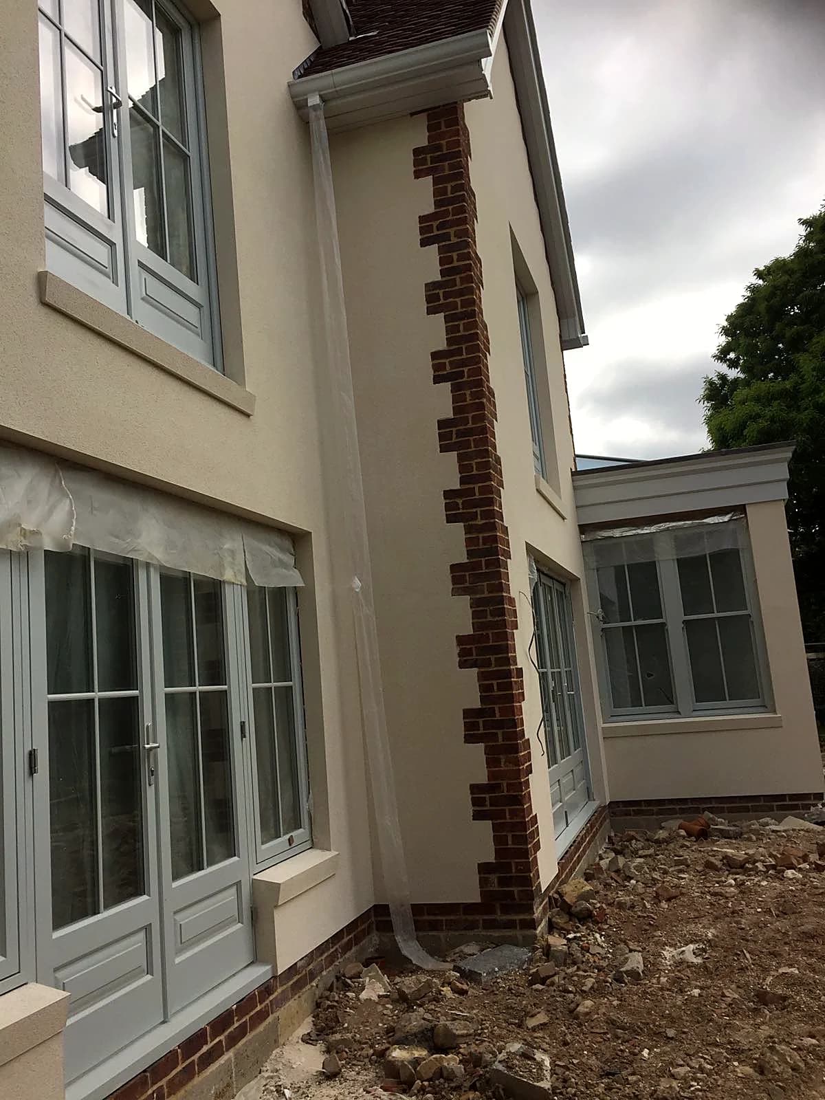 Light grey timber French doors and sash windows with brick quoin detailing
