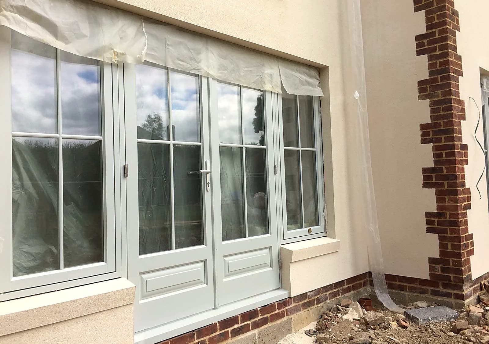 Light grey timber French doors flanked by sash windows