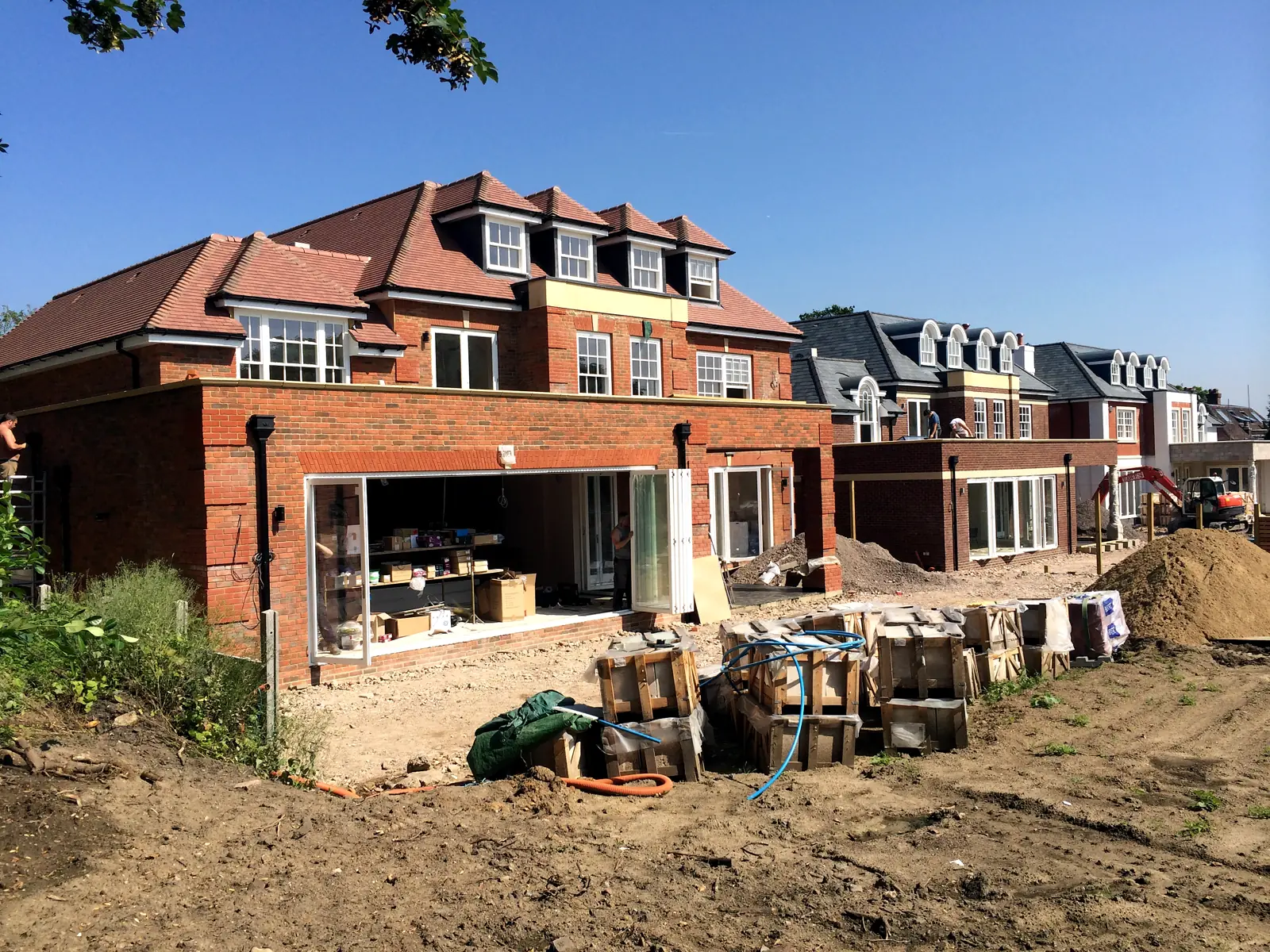 The Surrey new-build homes during construction with timber windows and bifold doors being installed