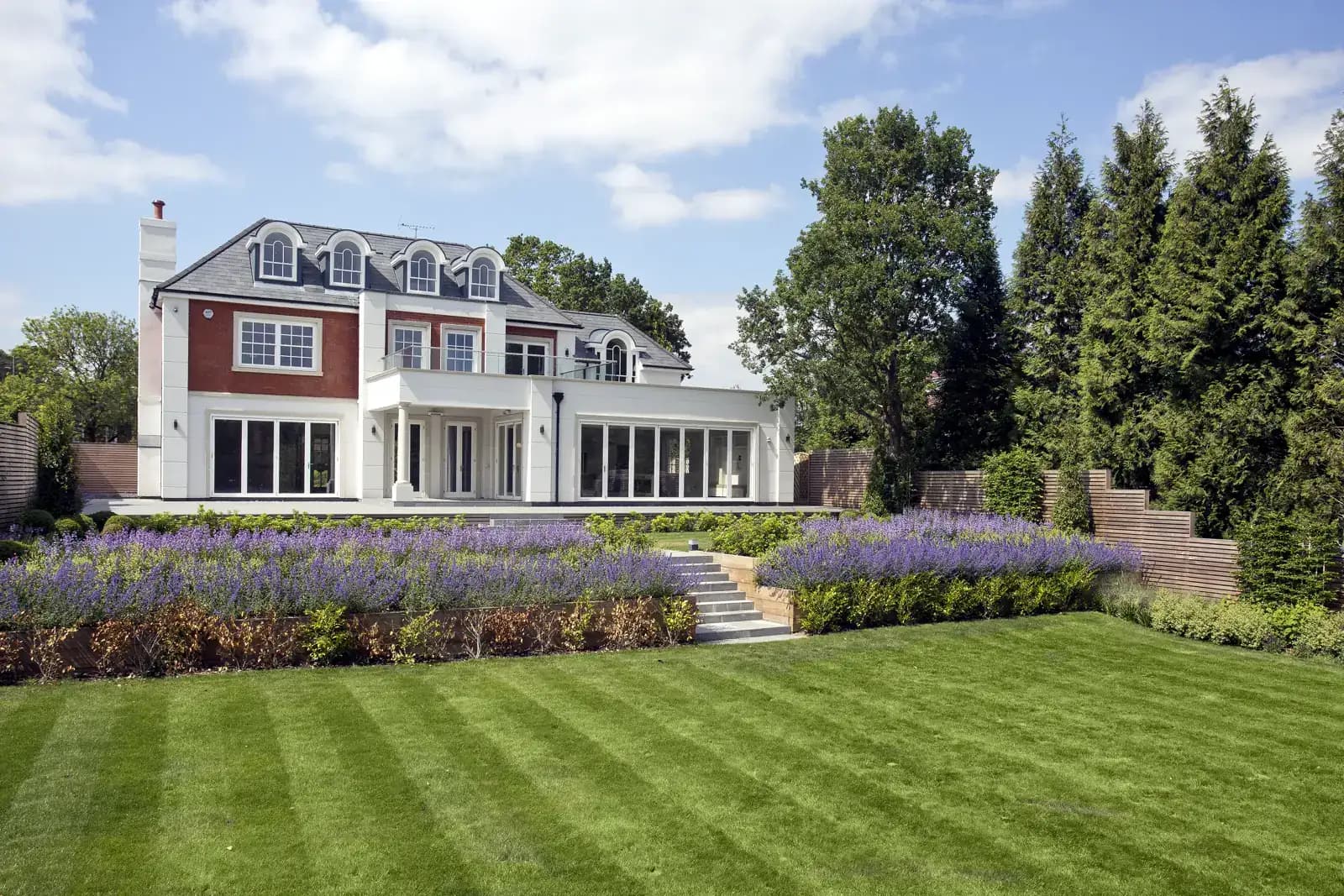 Garden elevation of a Surrey new-build home with timber sash windows, lavender and lawn
