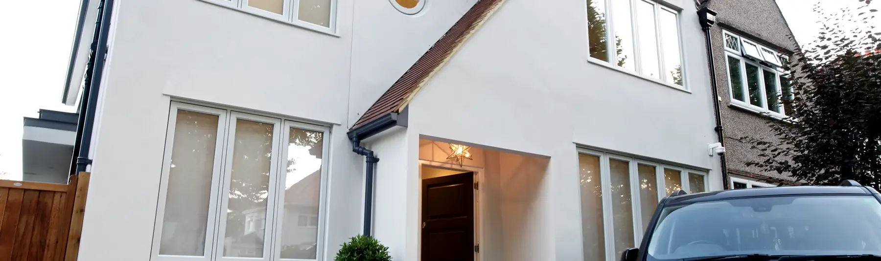 White rendered period house with white timber casement windows and an oval gable window