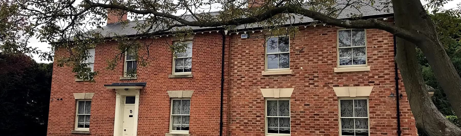 Red-brick period house with white timber Victorian sash windows across the elevation