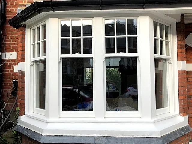 White timber splayed bay sash window with multi-pane upper sashes in red brick