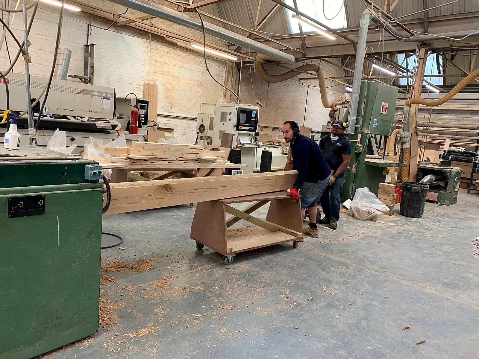 Two of our craftsmen moving a length of timber in our Worcestershire joinery workshop